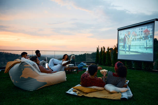 Friends watching a movie together on a projector screen at sunset